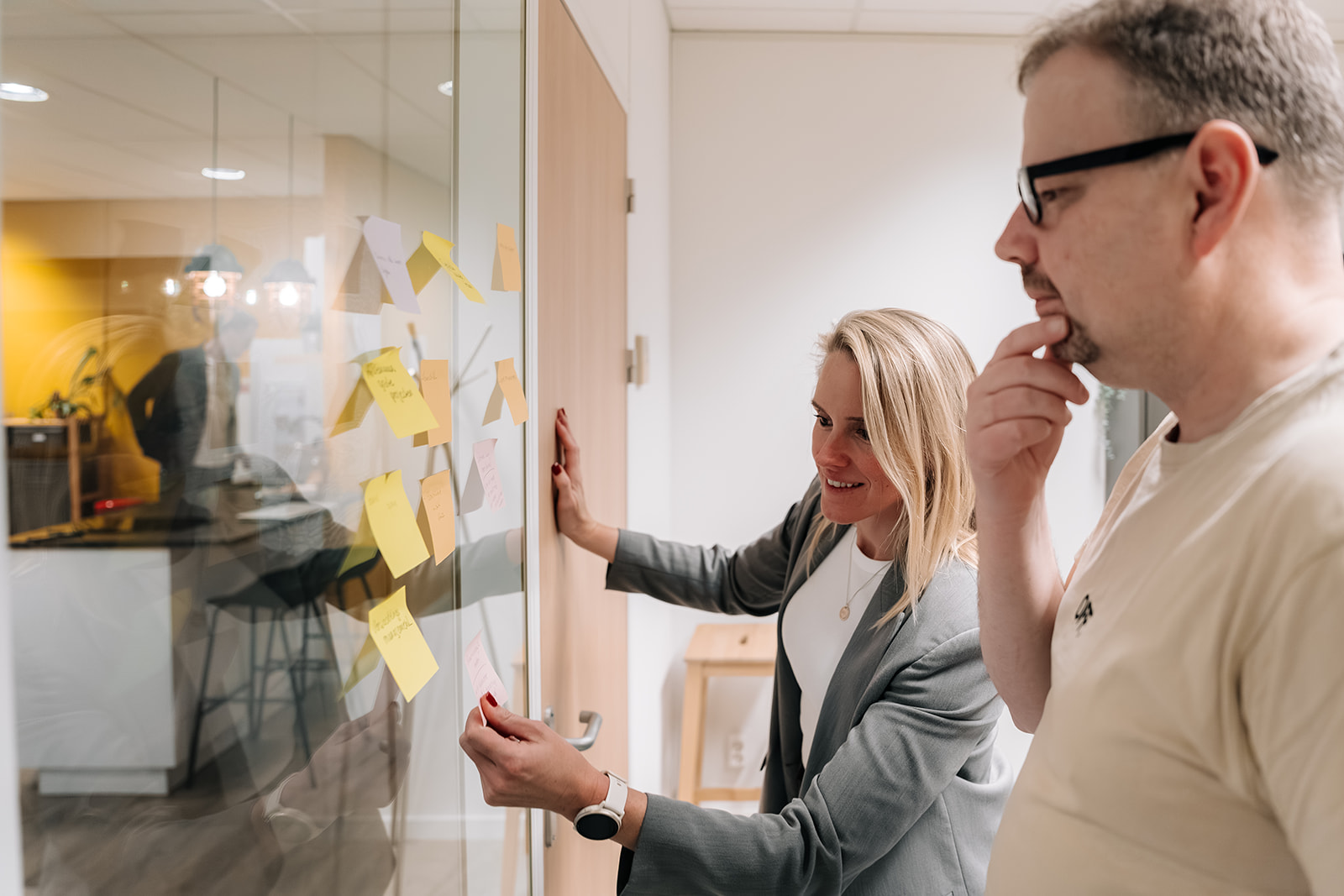 Collega's kijken en denken na over post-its op het raam