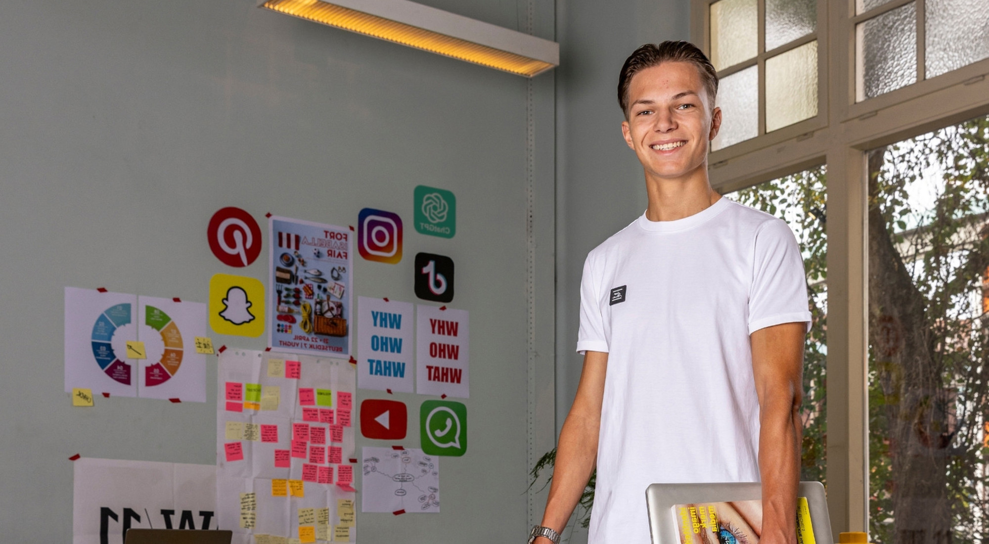 lachende jongen voor muur met logo's van social media platformen