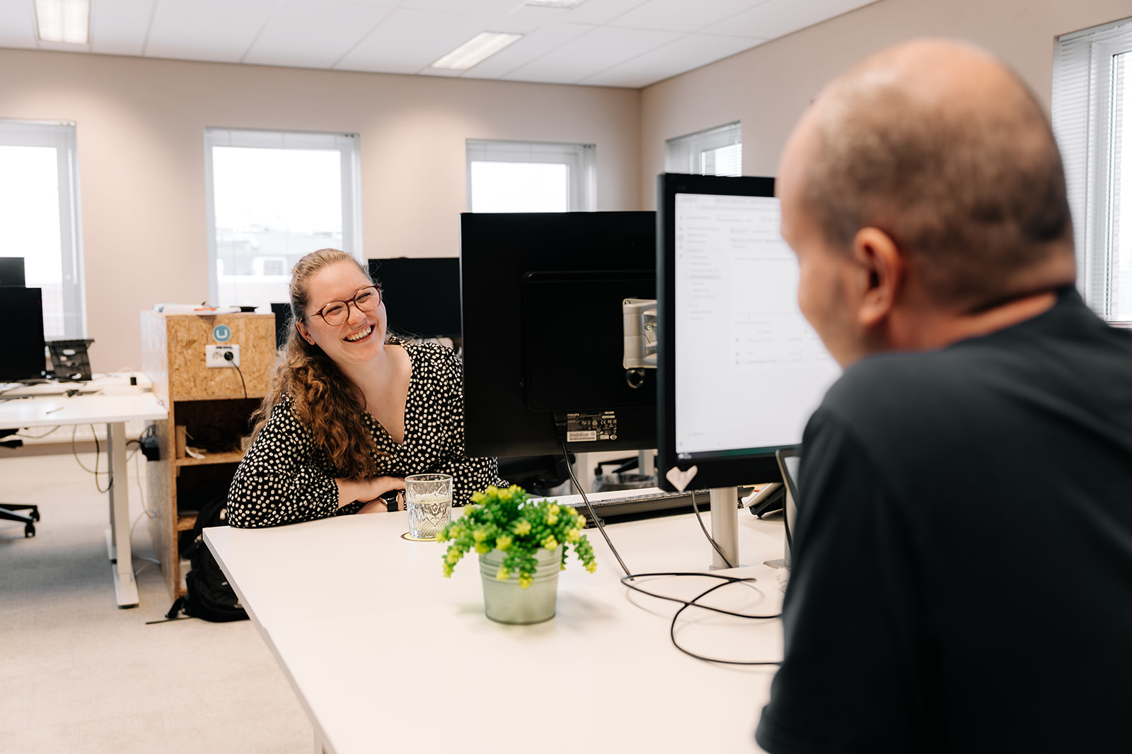 twee collega's op werkplek met elkaar overleggen