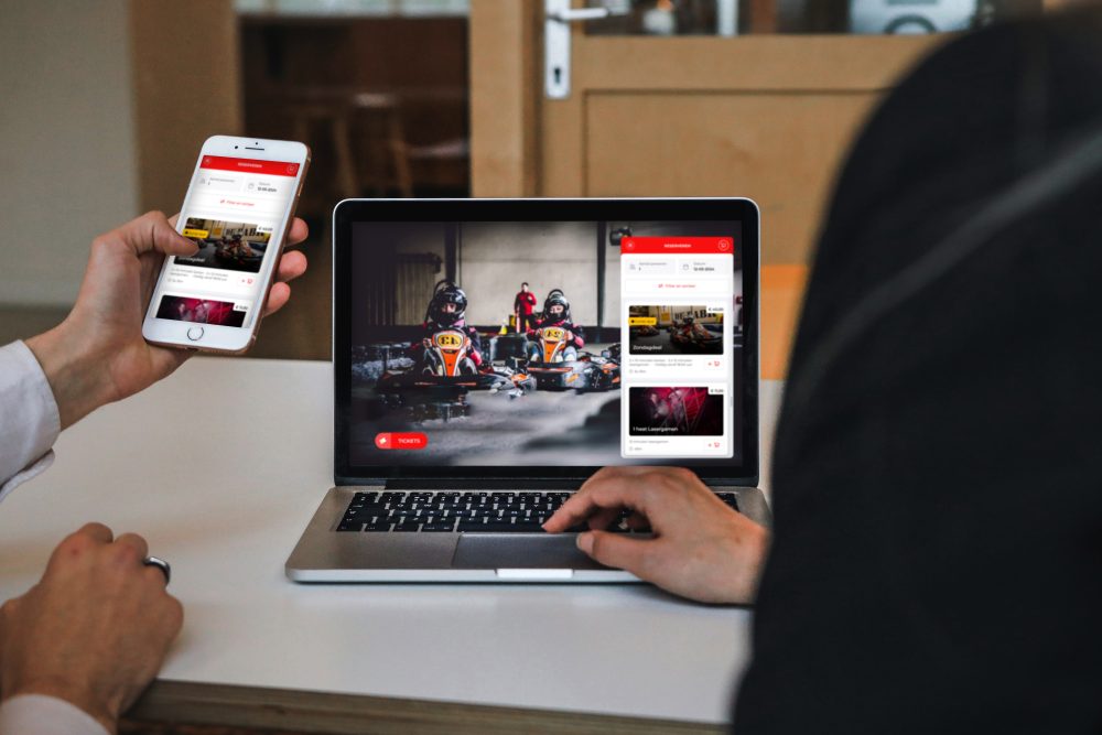 Twee mensen bekijken een responsive website met kart-racingafbeeldingen op laptop en smartphone