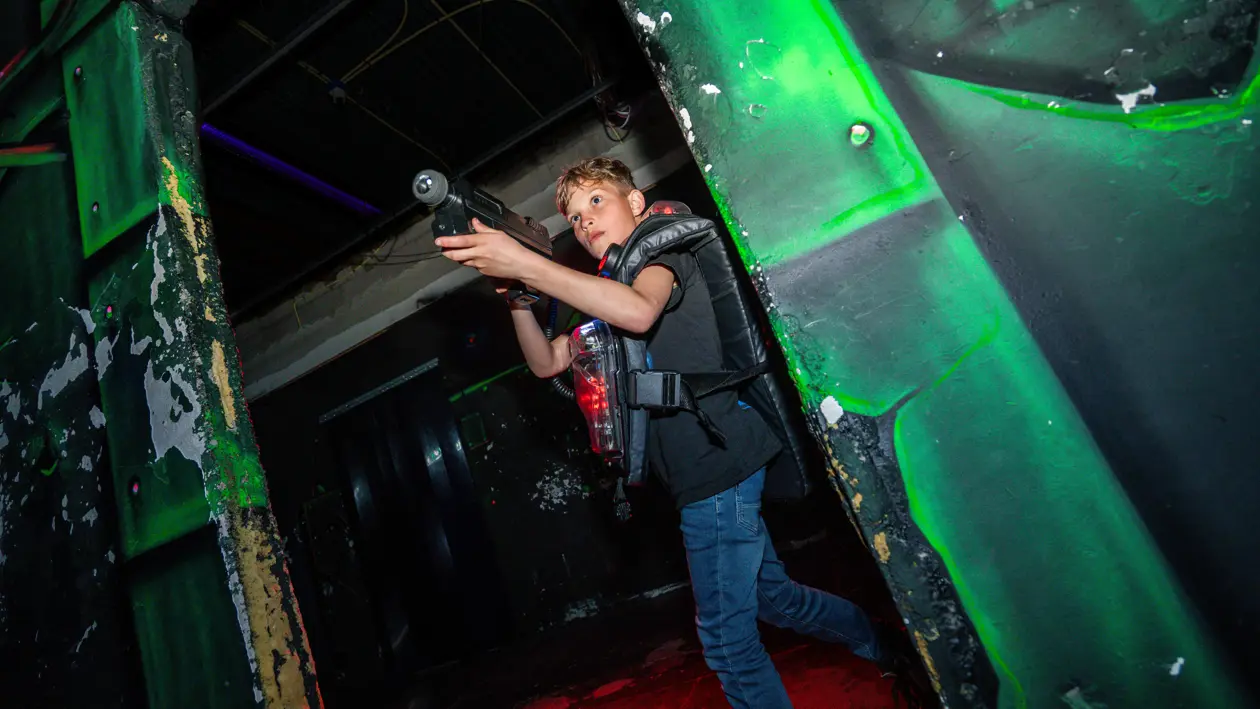 jongen met lasergame in donkere ruimte