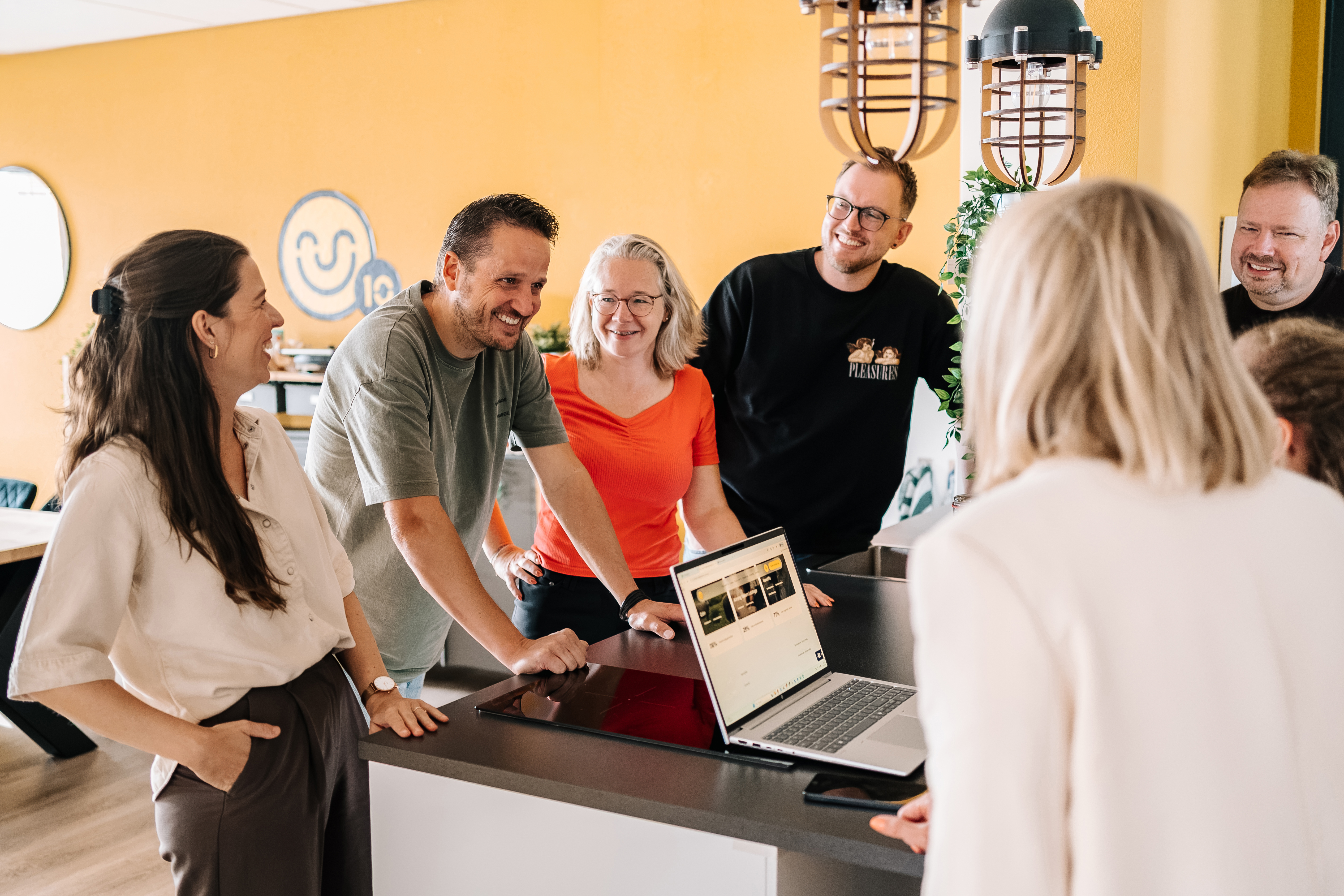 team kijkend naar elkaar met in het midden een laptop