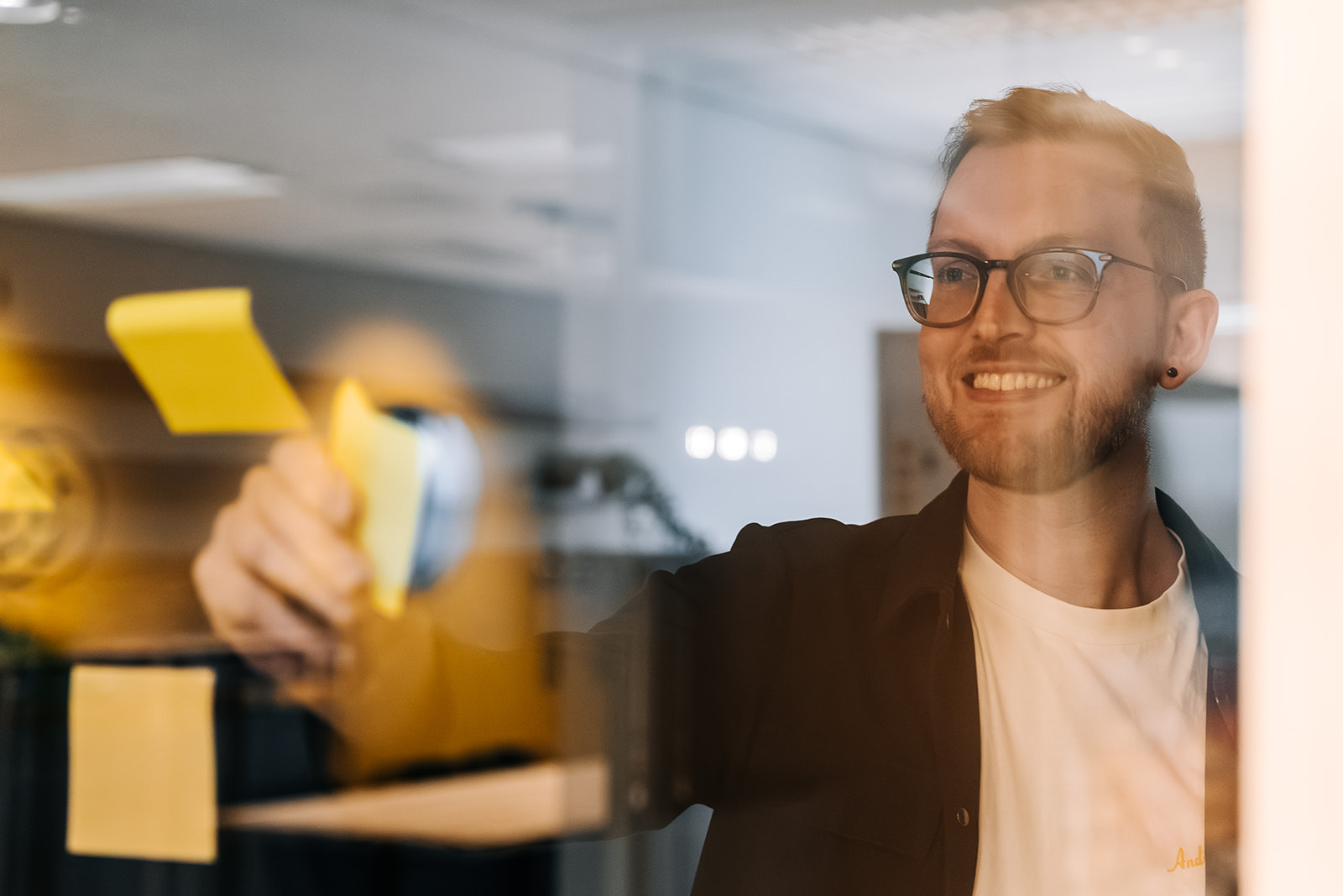 Lachende man plakt post-it op raam
